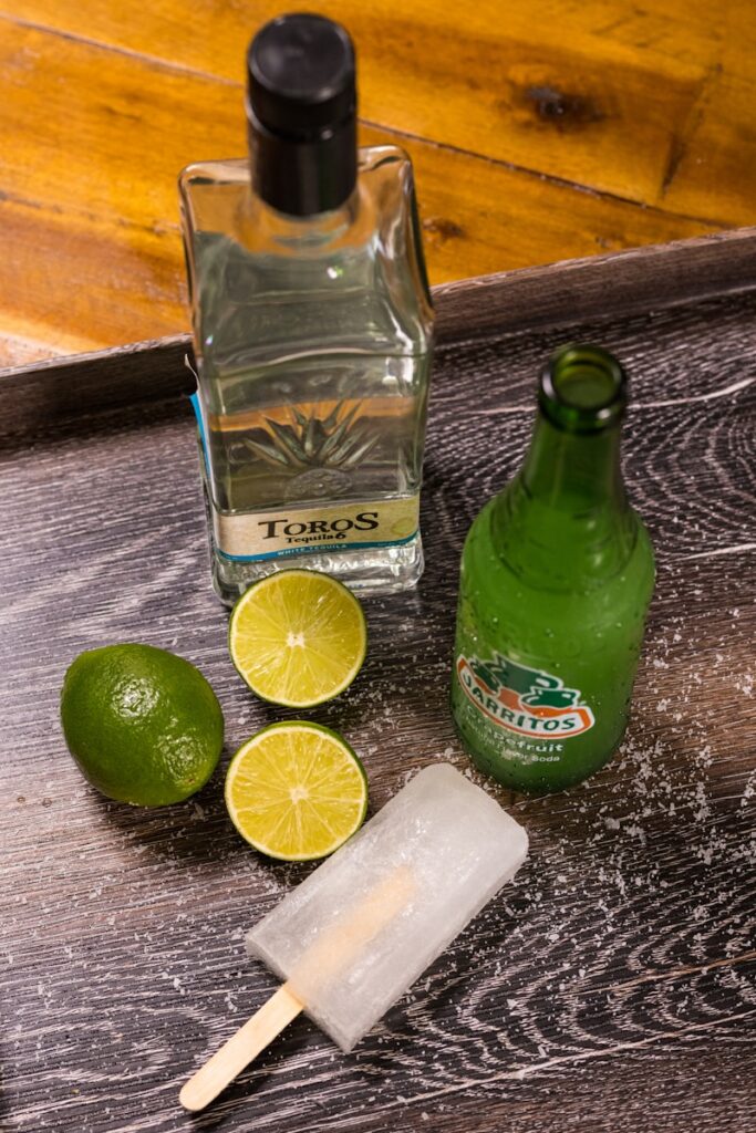 green glass bottle beside sliced lemon